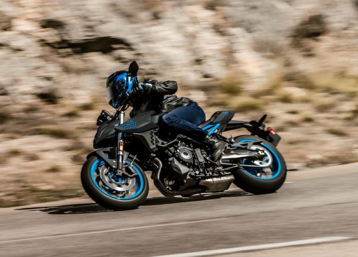 Rider leaning a blue naked street motorcycle through a corner