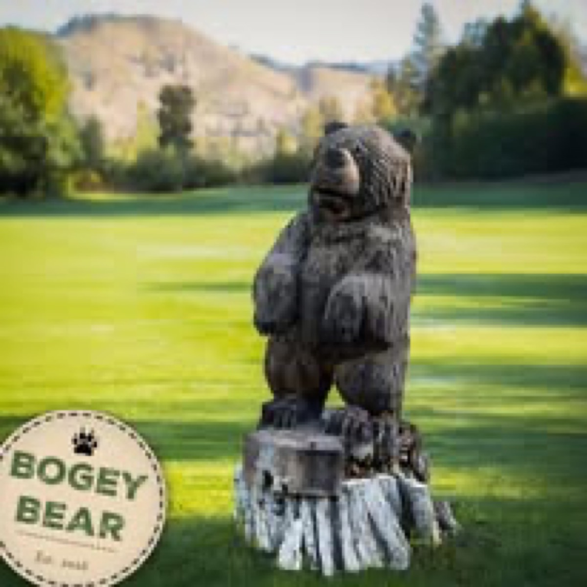 Carved wooden bear statue on a golf course green beside a Bogey Bear sign