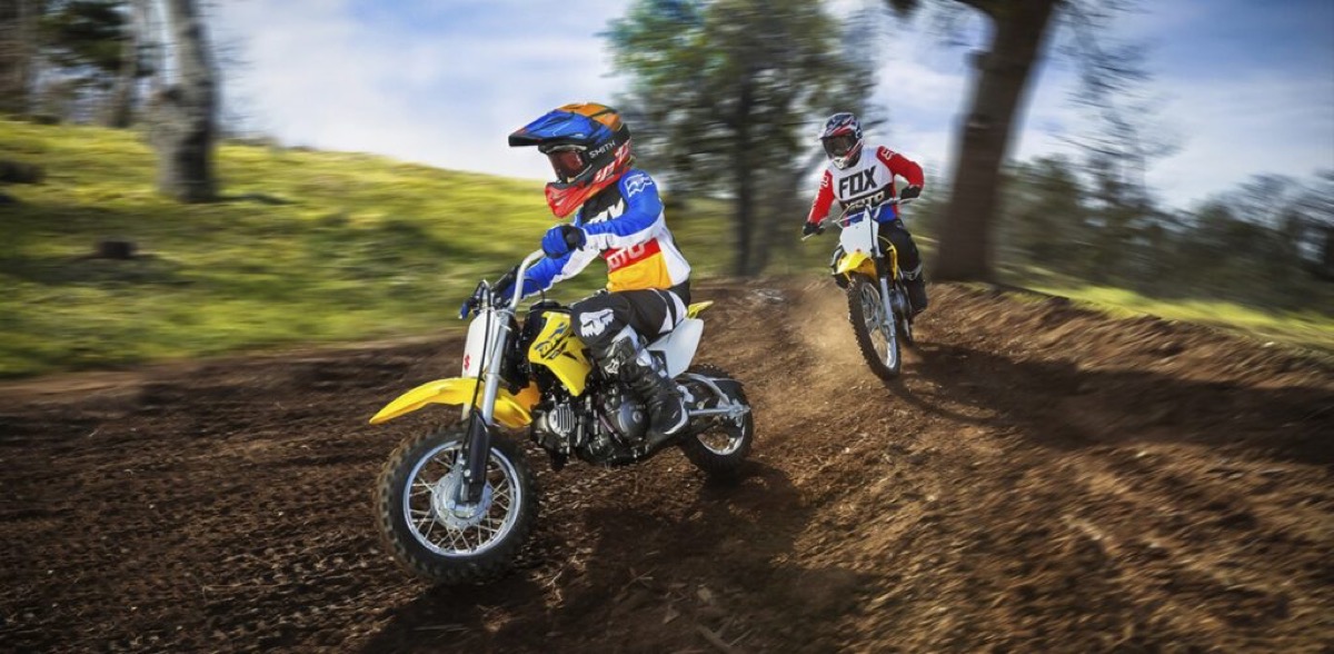 Two riders racing Suzuki RM-Z motocross bikes on a dirt track