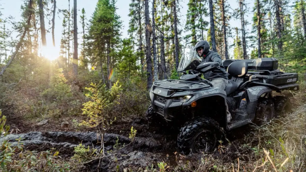 Camouflage Suzuki KingQuad loaded with gear on a forest trail at sunrise