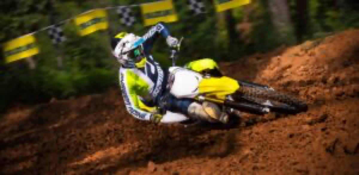 Rider railing a berm on a yellow Suzuki RM-Z motocross bike